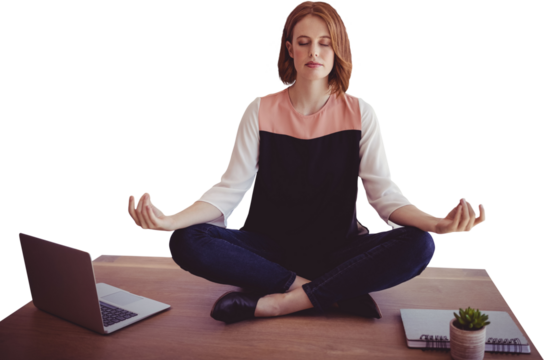 Businesswoman meditating while sitting on desk - Powered by Adobe