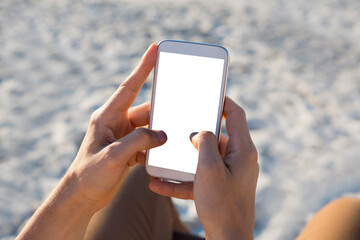 hands of man using mobile phone at beach