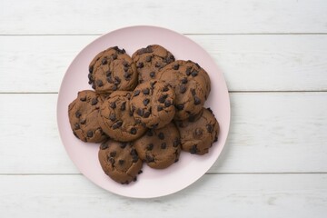chocolate chip cookies on a pink plate on a white wooden table