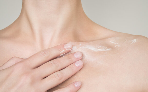 a woman applies moisturizing lotion to the décolleté area. skin care concept