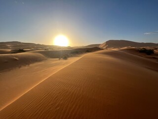 Obraz na płótnie Canvas Dunes in the Sahara desert, Merzouga desert, grains of sand forming small waves on the dunes, panoramic view. Setting sun. Morocco 