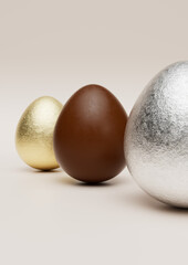 Milk chocolate easter eggs with gold and silver Aluminium foil on pale background.	
