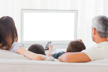 Family sitting on sofa watching television together