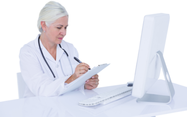 Female doctor writing on clipboard while sitting at desk