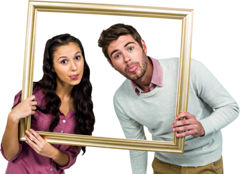 Couple sticking out tongue while holding picture frame 