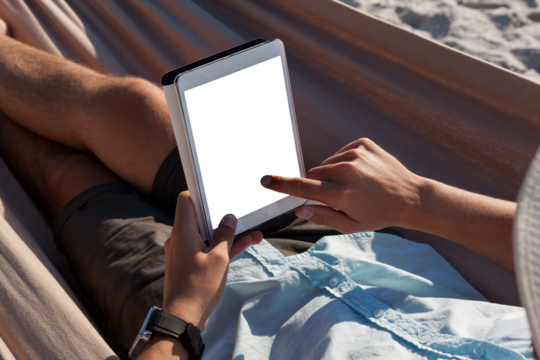 Man relaxing on hammock and using digital tablet on the beach
