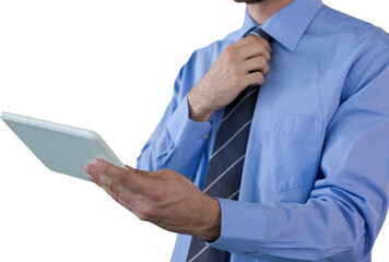 Midsection of businessman adjusting necktie while holding tablet