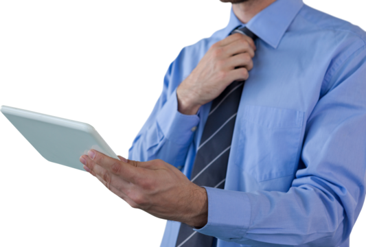 Midsection of businessman adjusting necktie while holding tablet