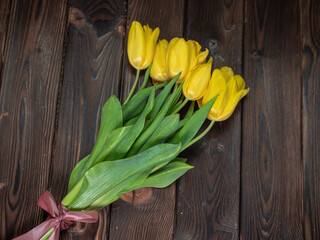 Yellow tulips lie on a wooden rustic table. Spring holidays concept background and mother day.