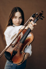 Fototapeta na wymiar A beautiful girl holds a violin in her hands. Violinist in white shirt and jeans