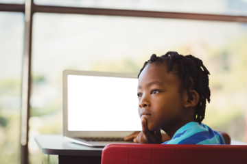 Thoughtful boy sitting by laptop