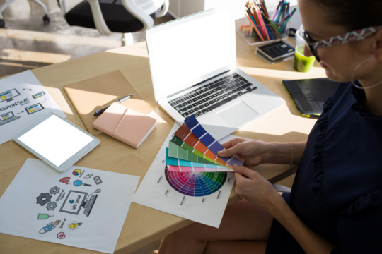 Female executive holding color swatch at desk in officeFemale executives holding color shade swatch 