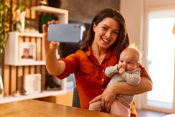 A smiling mom makes a photo on her mobile phone with her cute baby girl.