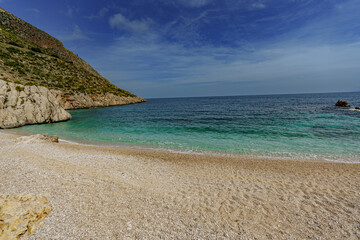 Obraz premium A beautiful view of the calm sea and the sandy beach surrounded by rocks