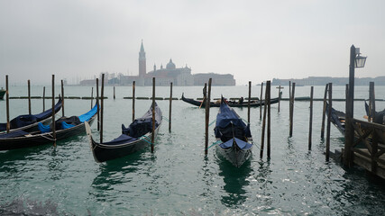 Wenecja, laguna, lido, zamglony port, przycumowane gondole w tle kościół, klasztor, opactwo,...