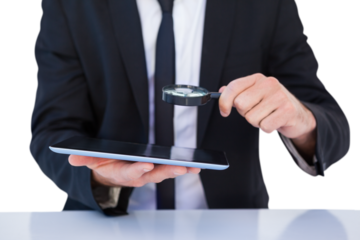 Businessman looking at his tablet through magnifying glass