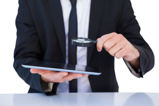 Businessman looking at his tablet through magnifying glass - Powered by Adobe