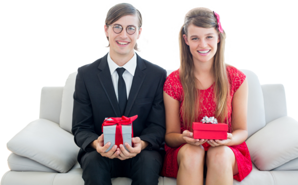 Cute geeky couple smiling and holding gift 
