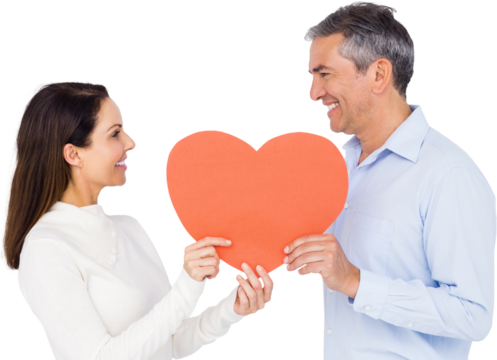 Smiling couple holding heart shape paper