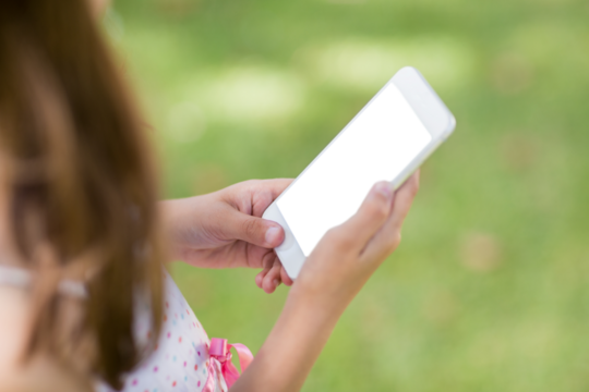Girl holding smart phone at park