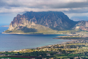 A beautiful seaside mountain covered with a dark rainy cloud below with a town.