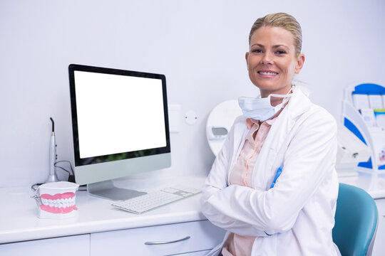 Portrait of smiling dentist working while sitting by computer