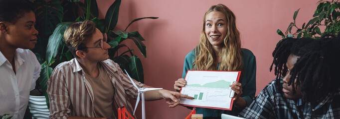 Diverse group of international students working on the urban project of modern city with renewable energy source, green areas. Concept of ecology, environment, waste recycling, technology banner