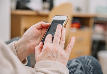 Elderly woman holding and using smartphone, mobile phone. Grandmother. Close up view, family connection concept.