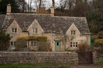 Fototapeta na wymiar Iconic row of medieval stone built cottages in the picturesque village of Bibury in Cotswolds, England