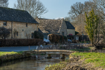 Fototapeta na wymiar Iconic medieval built houses next to River Eye in Lower Slaughter in Cotswolds England