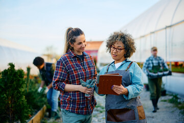 Naklejka premium Young worker and her manager using touchpad while working at garden center.
