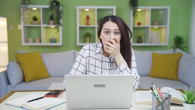 Young business woman looking at camera with amazement and amazement.
The young woman working from home is shocked and amazed by the events she hears.
