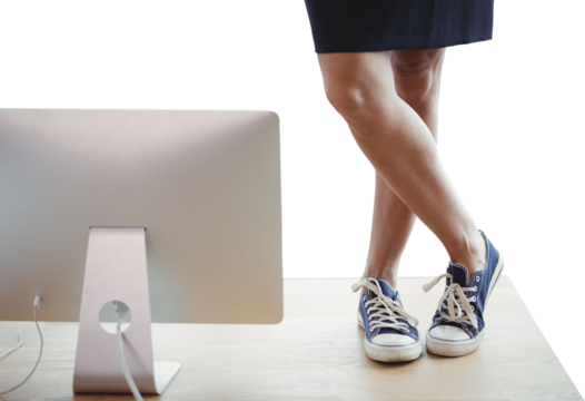 Low section of businesswoman standing on table by computer