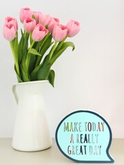ramo de tulipanes rosa en un jarrón blanco con un letrero decorando una mesita