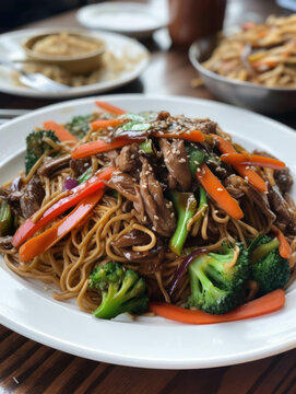 A plate of grilled vegetable lo mein served over a bed of saucy beef.. AI generation.