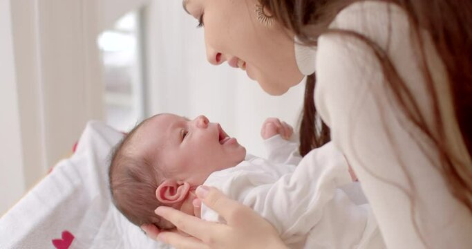 young mother gently kisses hands small child, surge hormone oxytocin. The child opens mouth, looks his mother. She zips up her bodysuit. Communication between mother and child.