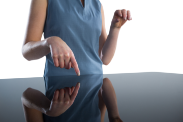 Mid section of businesswoman using imaginary interface at table