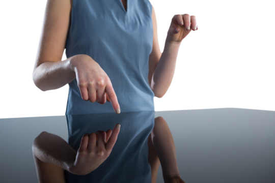 Mid section of businesswoman using imaginary interface at table