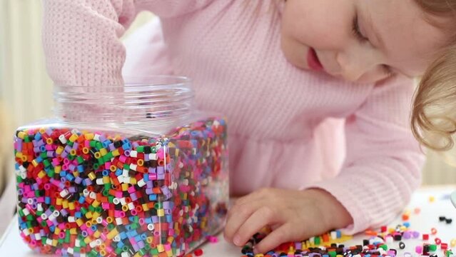 Toddler Playing with Colorful Beads in Close-up Shot, Focusing on Her Hair