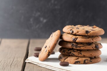 chocolate chip cookies on wooden table, stack of chocolate chip cookies on a wooden table, chocolate chip cookies on top of white dish towel on a white wooden table