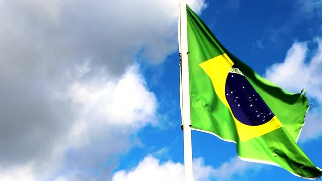 Flag of Brazil. The Brazilian flag on a flagpole at the background blue sky with beautiful clouds. In Brazil their national flag is called Bandeira do Brasil.  Waving Brazil Flag, 4K video