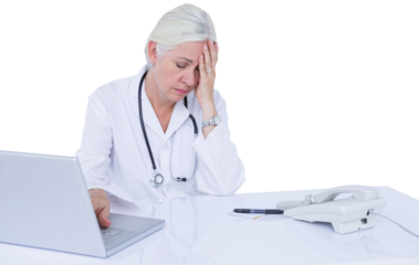 Tired female doctor using laptop at desk