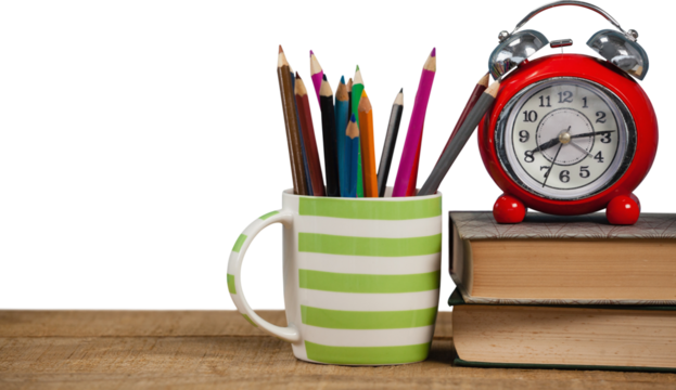 Books with alarm clock by colored pencils in mug on table