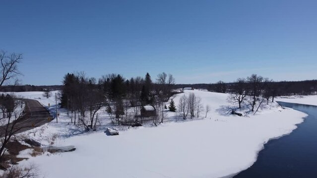 Aerial shot descending from above a snowy farm and river scene