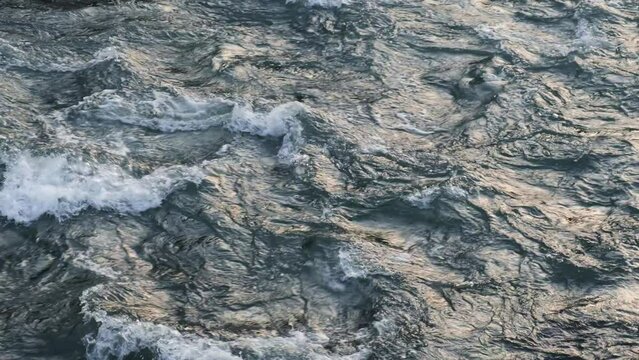 Mountain river with fast moving water, beautiful turbulence patterns of wild steam, seamlessly looped video, top view.