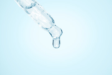 Cosmetic pipette with dripping liquid and drops on the south, blue background, serum, serum, gel, vitamin, water, oil.