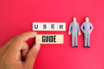 Hand holding a miniature of a man with the word User Guide alphabet letters. user or customer guide...