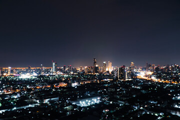 Fototapeta premium Blur background buildings metropolitan condo high street road blurry bokeh light nightlife dark sky night. Defocused blurred thailand Bangkok landscape building with street way. Business background