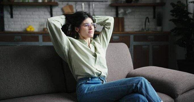 Black-haired transgender woman enjoys relaxation on sofa
