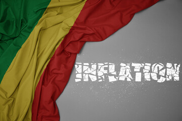 waving colorful national flag of republic of the congo on a gray background with broken text inflation. 3d illustration